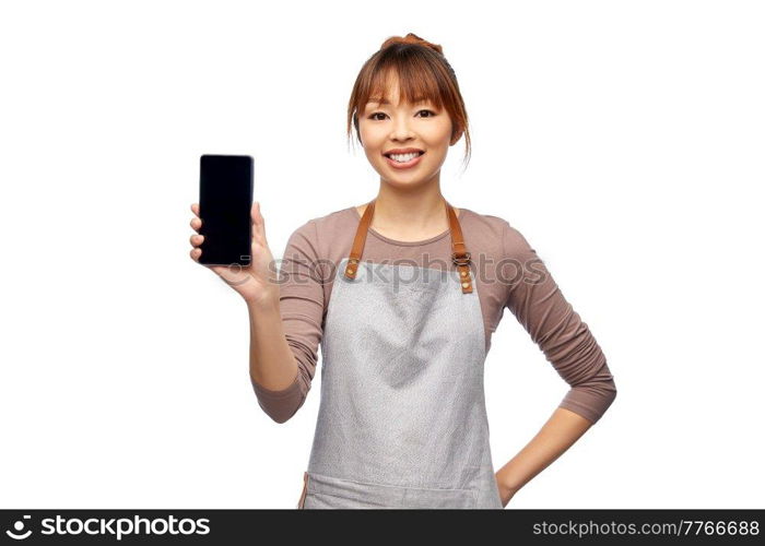 cooking, technology and people concept - happy smiling female chef or waitress in apron showing smartphone with empty screen over white background. happy woman in apron showing smartphone