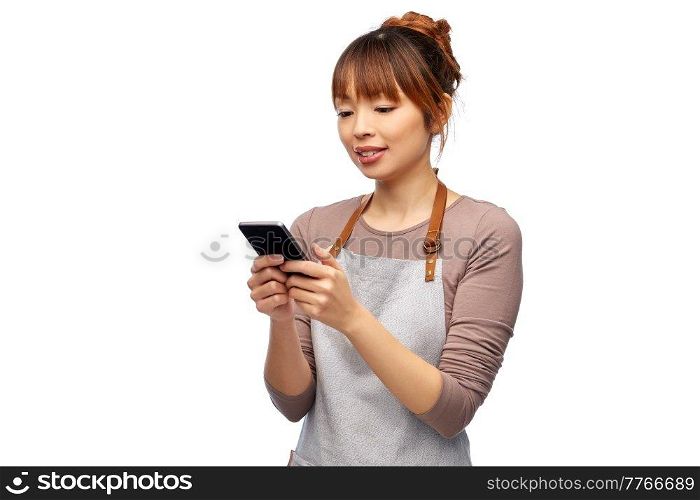 cooking, technology and people concept - happy smiling female chef or waitress in apron showing smartphone with empty screen over white background. happy woman in apron showing smartphone