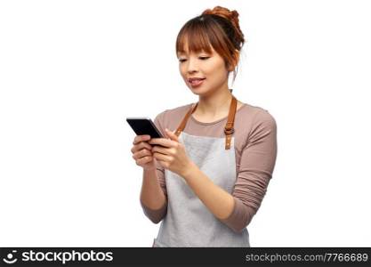 cooking, technology and people concept - happy smiling female chef or waitress in apron showing smartphone with empty screen over white background. happy woman in apron showing smartphone