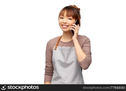 cooking, technology and people concept - happy smiling female chef or waitress in apron calling on smartphone over white background. happy woman in apron calling on smartphone