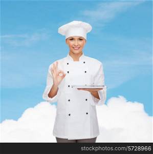 cooking, technology and people concept - smiling female chef, cook or baker with tablet pc computer showing ok gesture over blue sky with cloud background