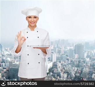 cooking, technology and people concept - smiling female chef, cook or baker with tablet pc computer showing ok gesture over city background