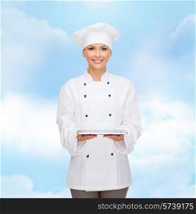 cooking, technology and people concept - smiling female chef, cook or baker with tablet pc computer over blue cloudy sky background