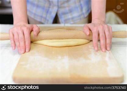 Cooking: woman rolling out the dough on cutting board, close-up shot