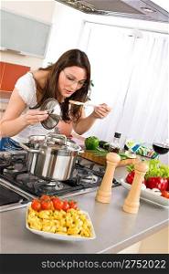 Cooking - young woman in modern kitchen with vegetable and pasta