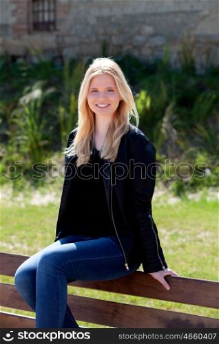 Cool blonde girl sitting on a wooden bench in the park