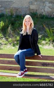 Cool blonde girl sitting on a wooden bench in the park