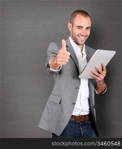 Cool businessman using touchpad on grey background