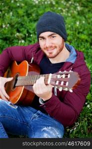 Cool handsome guy with beard playing guitar at outside