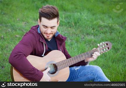 Cool handsome guy with beard playing guitar at outside