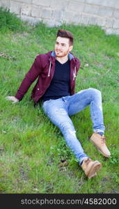 Cool handsome guy with beard sitting on the grass