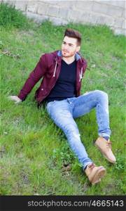Cool handsome guy with beard sitting on the grass