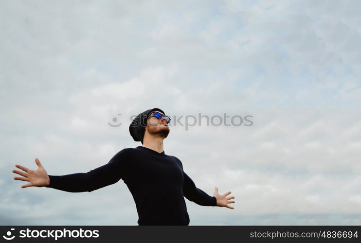 Cool handsome guy with his arms extended with the sky of background