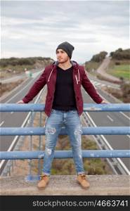 Cool handsome man at the top of a bridge over a highway
