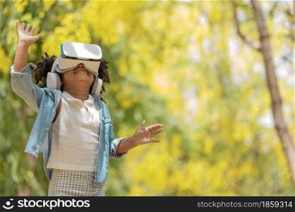 Cool millennial child exploring space with virtual reality glasses at outdoor