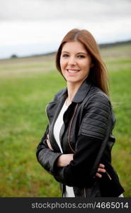 Cool pretty woman walking through the meadow with a leather jacket