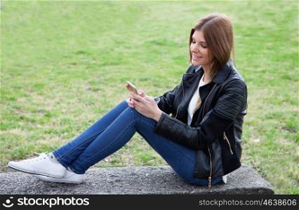 Cool pretty woman with the mobile sitting on a bank at the park