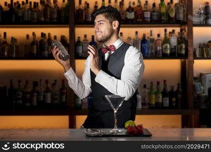 Cool professional bartender making a cocktail, shaking a cocktail shaker. Authentic barman making alcohol beverages in modern bar. High quality photo.. Cool professional bartender making a cocktail, shaking a cocktail shaker. Authentic barman making alcohol beverages in modern bar.