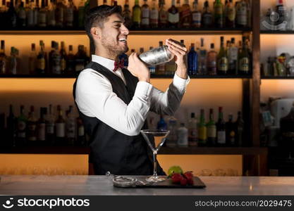 Cool professional bartender making a cocktail, shaking a cocktail shaker. Authentic barman making alcohol beverages in modern bar. High quality photo.. Cool professional bartender making a cocktail, shaking a cocktail shaker. Authentic barman making alcohol beverages in modern bar.