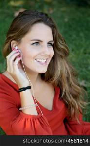 Cool woman in a park in summer smiling and listening to music on the headphones