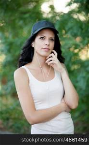 Cool woman with hat and headphones listening music walking in the forest
