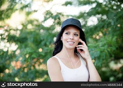 Cool woman with hat and headphones listening music walking in the forest
