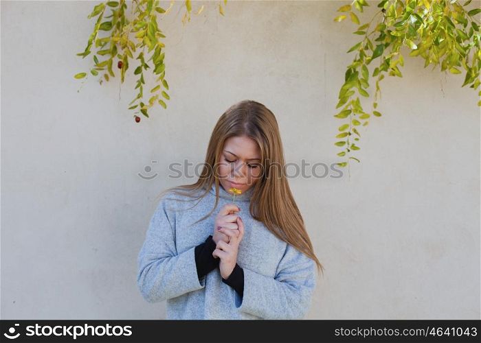 Cool young girl smelling a yellow flower in a sunny day