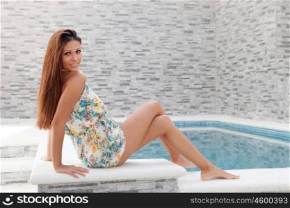 Cool young woman sitting on the edge of the pool