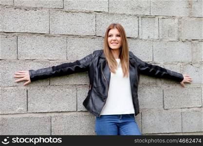 Cool young woman with black leather jacket and a grey wall of background