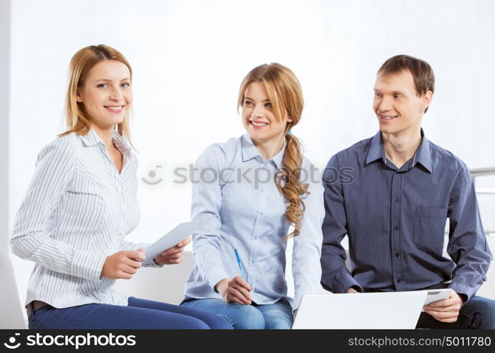 Cooperate for productive work. Three co-workers discussing business ideas in office
