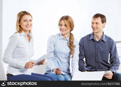 Cooperate for productive work. Three co-workers discussing business ideas in office