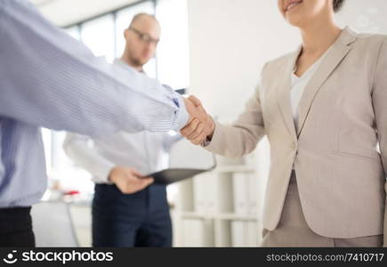 cooperation, collaboration and partnership concept - close up of business partners making handshake at office. close up of business people making handshake