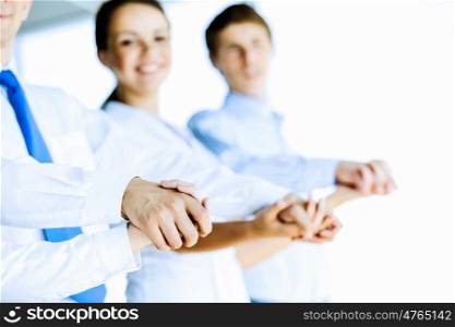 Cooperation concept. Image of group of businesspeople holding arms together. Teamwork