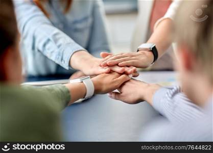 cooperation, corporate and team work concept - close up of business team stacking hands at office. close up of business team stacking hands