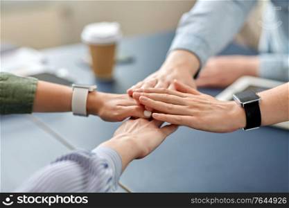 cooperation, corporate and team work concept - close up of business team stacking hands at office. close up of business team stacking hands