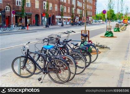 Copenhagen city street with bicycles parking at sidewalk, focus on foreground, Denmark