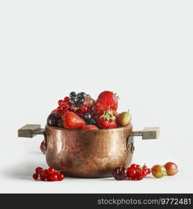 Copper cooking pot with fresh fruits and berries st white background