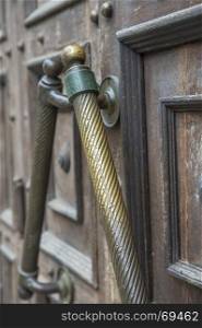 copper door handle on a brown wooden door to a public building