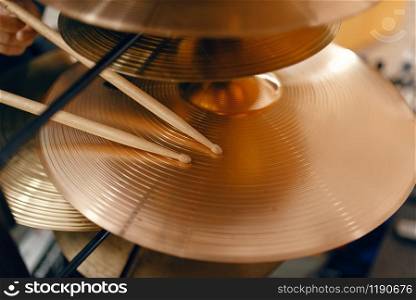 Copper drum cymbals and drumsticks on showcase in music store, closeup view, nobody. Assortment in musical instrument shop, professional equipment for musicians and performers