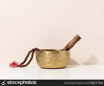 copper singing bowl and wooden clapper on a white table. Musical instrument for meditation, relaxation, various medical practices related to biorhythms, normalization of mental health