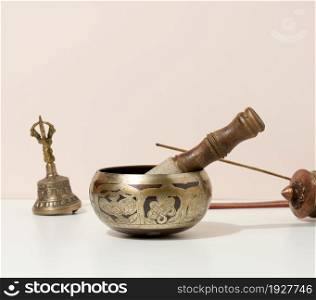 copper singing bowl and wooden clapper on a white table. Musical instrument for meditation, relaxation, various medical practices related to biorhythms, normalization of mental health