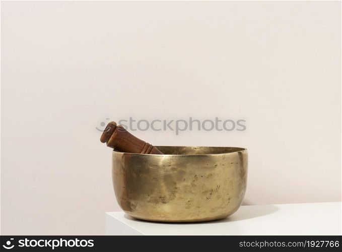copper singing bowl and wooden clapper on a white table. Musical instrument for meditation, relaxation, various medical practices related to biorhythms, in yoga