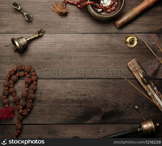 Copper singing bowl, prayer beads, prayer drum and other Tibetan religious objects for meditation and alternative medicine on a brown wooden background, copy space