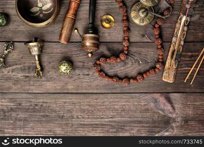 Copper singing bowl, prayer beads, prayer drum and other Tibetan religious objects for meditation and alternative medicine on a brown wooden background, copy space