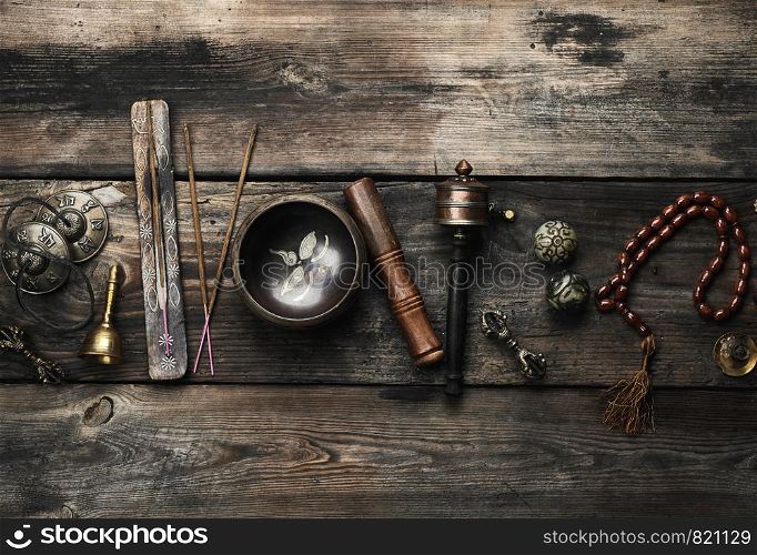 Copper singing bowl, prayer beads, prayer drum and other Tibetan religious objects for meditation and alternative medicine on a brown wooden background, copy space