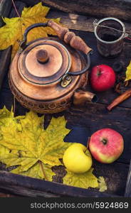 Copper teapot in the background osennih maple leaves and apples