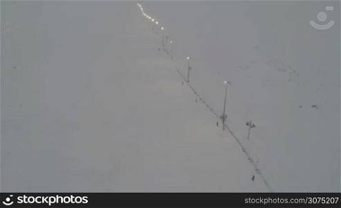 Copter shot of people using ski-lift for getting to the top of the ski slope