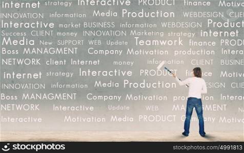 Copyright concept. Young businessman standing with back and painting different words on wall