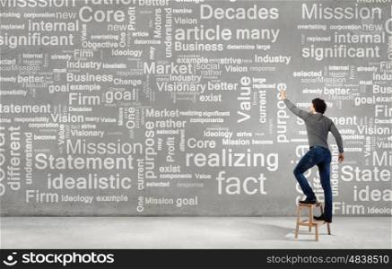 Copyright concept. Young businessman standing with back and writing different words on wall