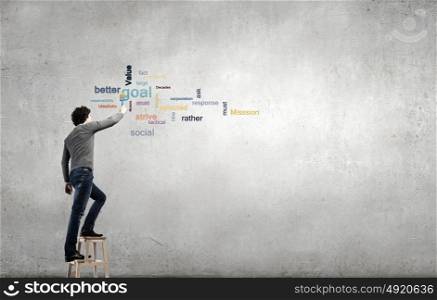 Copyright concept. Young businessman standing with back and writing different words on wall